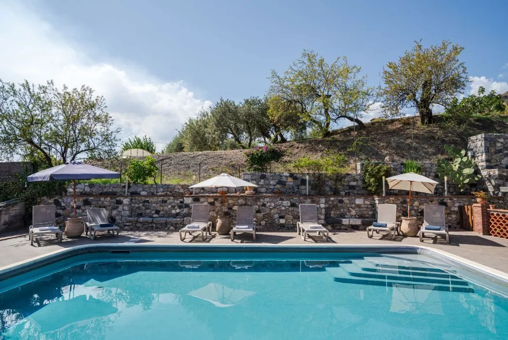 The villa pool with sun loungers and olive trees above Taormina